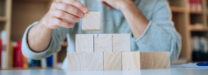 Bild zeigt Studierenden, der Holz-Bausteine übereinander stapelt