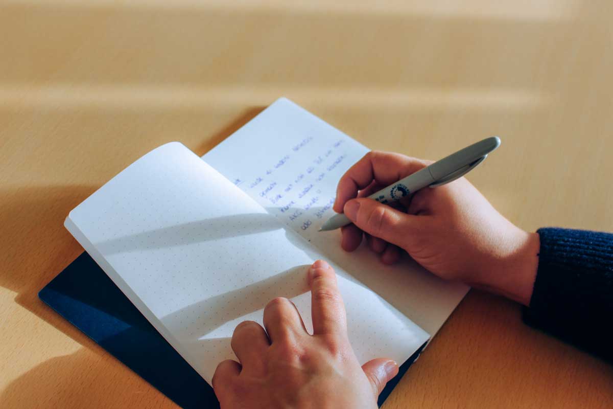 Person writes a diary entry in their notebook